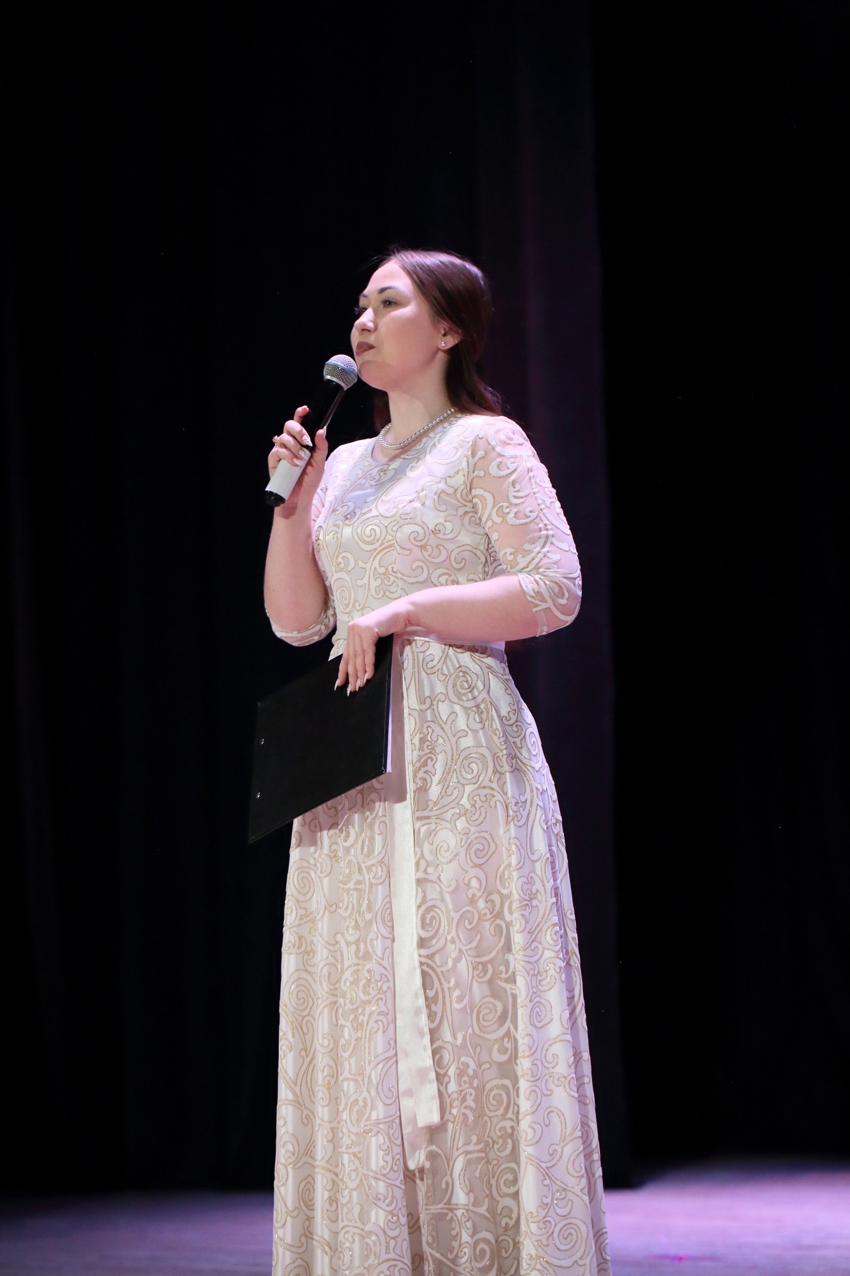 Ведущая на сцене в светлом платье